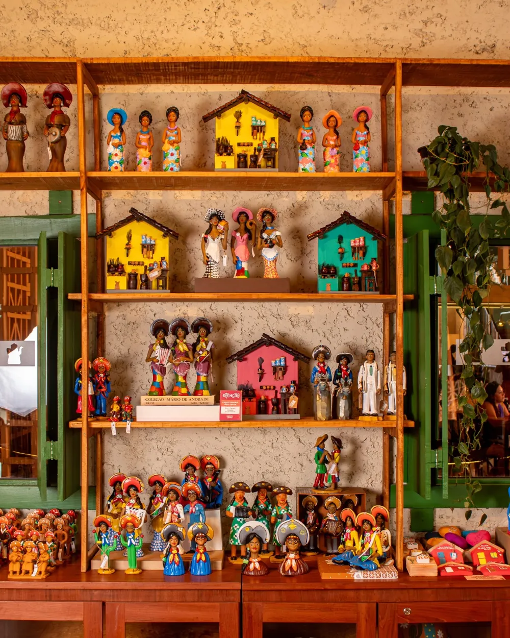 Estante com bonecos e casinhas coloridas de artesanato